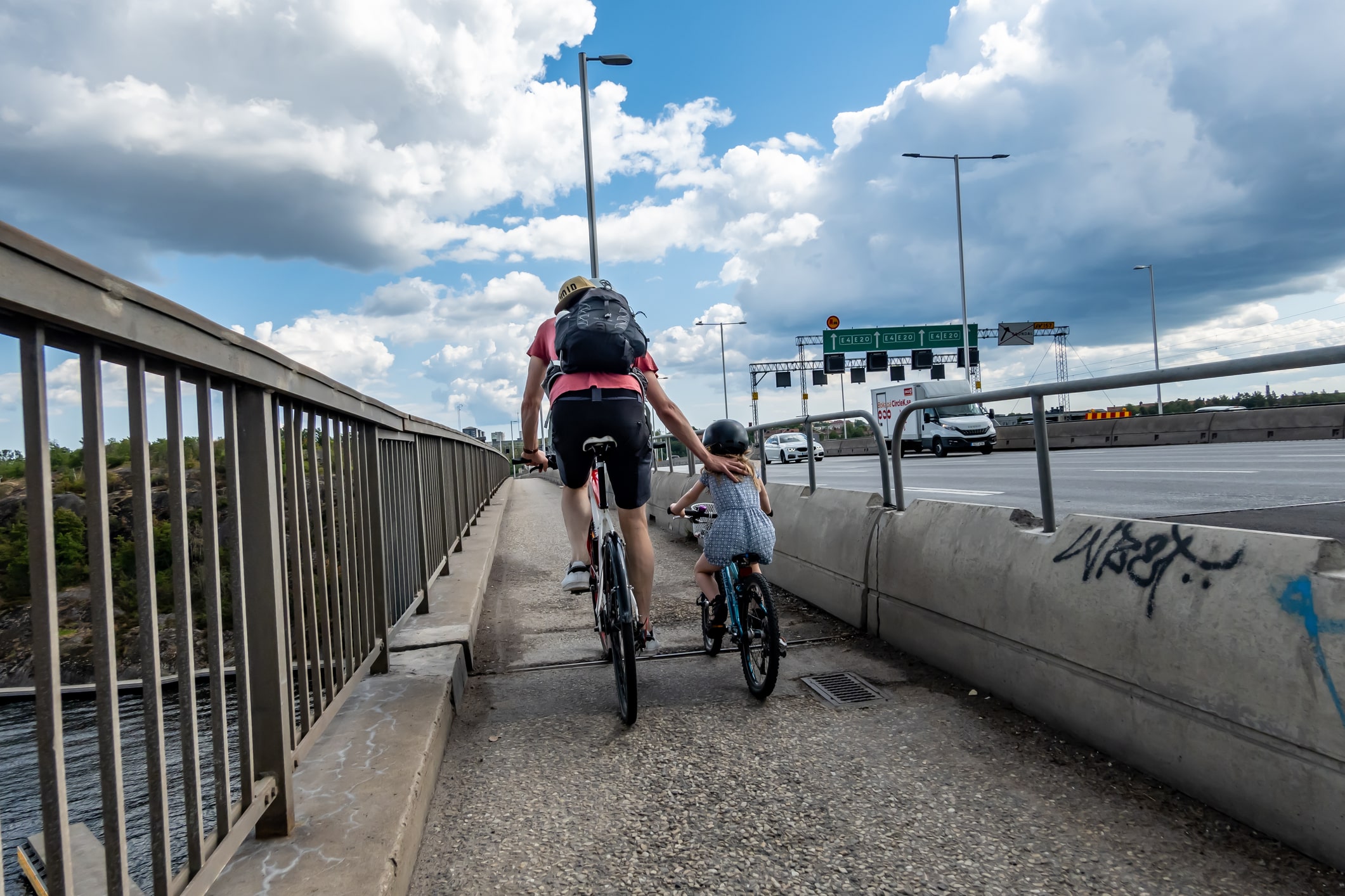 A father and daughter riding their bicycles on a bridge in Stockholm, Sweden.