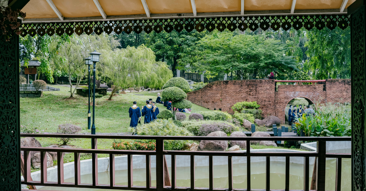 Graduates walking through a garden bridge